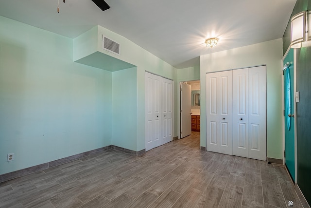 unfurnished bedroom with light wood-type flooring, ceiling fan, and multiple closets