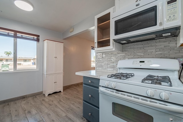 kitchen with tasteful backsplash, white appliances, blue cabinetry, white cabinets, and light hardwood / wood-style floors