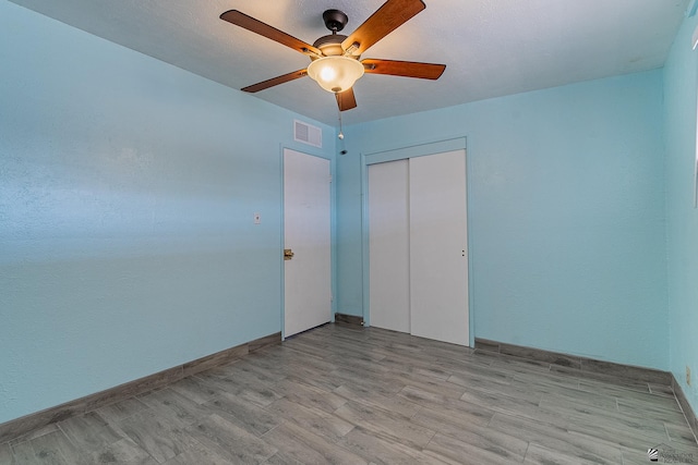 unfurnished bedroom with a closet, light hardwood / wood-style flooring, and ceiling fan