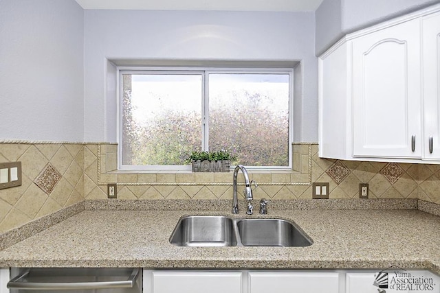 kitchen featuring light stone counters, sink, decorative backsplash, and white cabinets