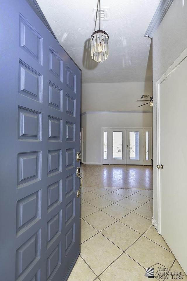 entryway with an inviting chandelier, light tile patterned floors, and french doors