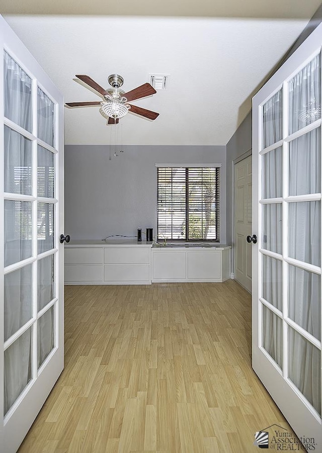 spare room with ceiling fan, vaulted ceiling, light hardwood / wood-style floors, and french doors