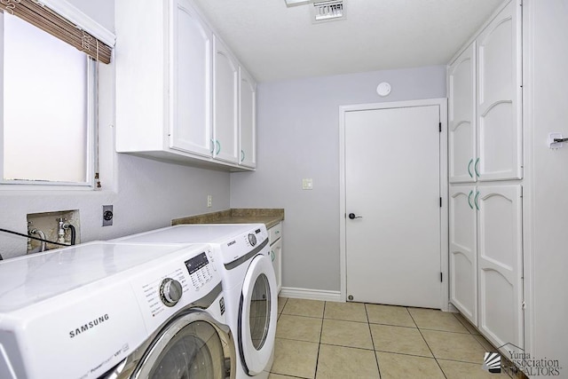 washroom with cabinets, washing machine and dryer, and light tile patterned floors