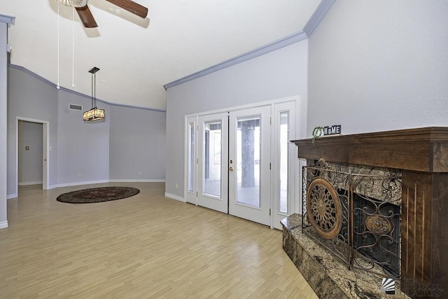 living room featuring a towering ceiling, light hardwood / wood-style flooring, ceiling fan, crown molding, and french doors