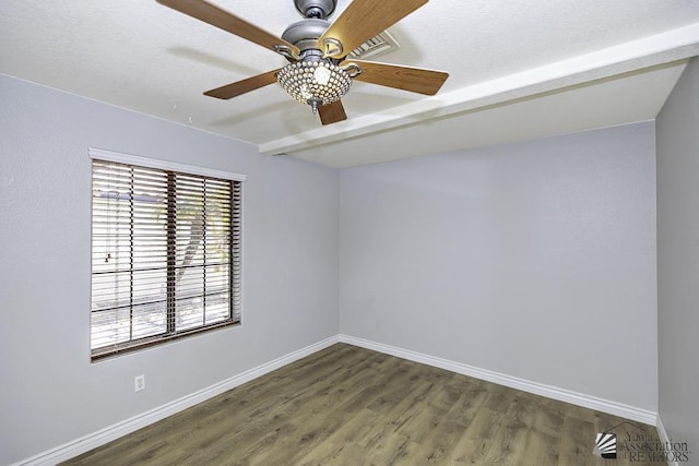 empty room with beam ceiling, dark wood-type flooring, and ceiling fan