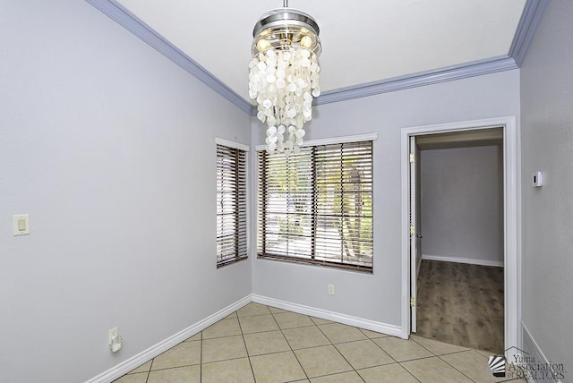 tiled spare room with crown molding and a chandelier