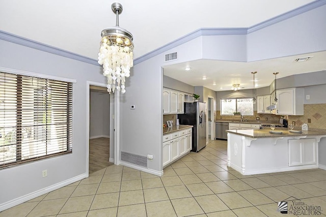 kitchen with decorative light fixtures, stainless steel appliances, kitchen peninsula, and white cabinets