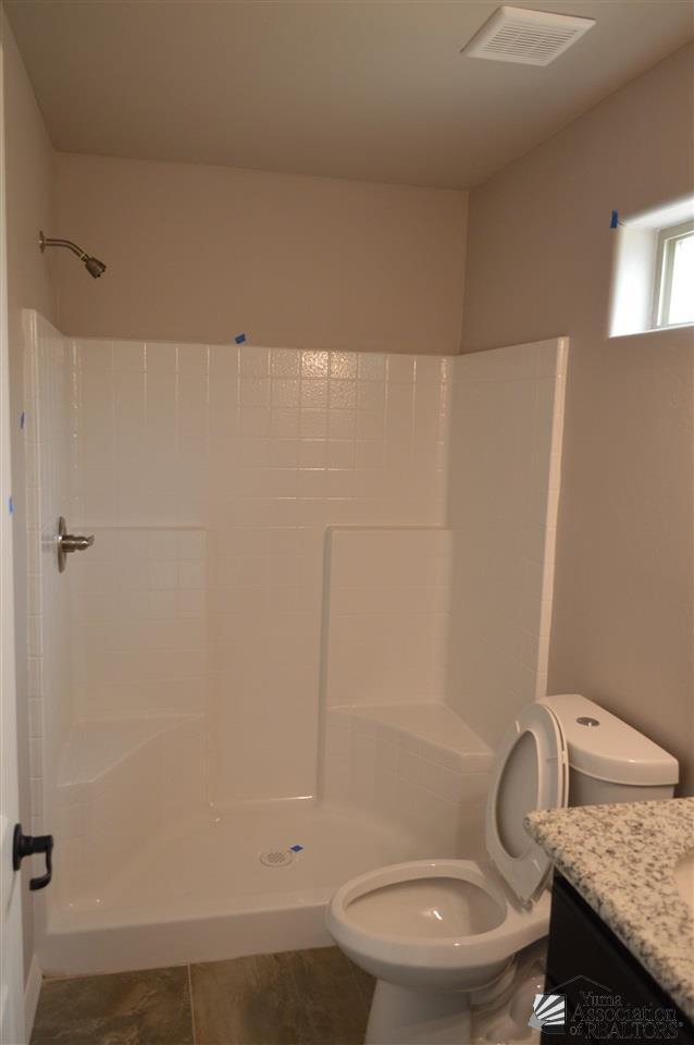 bathroom featuring a shower, vanity, and toilet