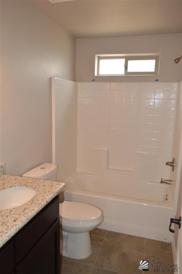 full bathroom featuring washtub / shower combination, vanity, tile patterned floors, and toilet