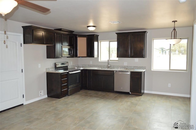 kitchen featuring light stone countertops, sink, ceiling fan, dark brown cabinets, and appliances with stainless steel finishes