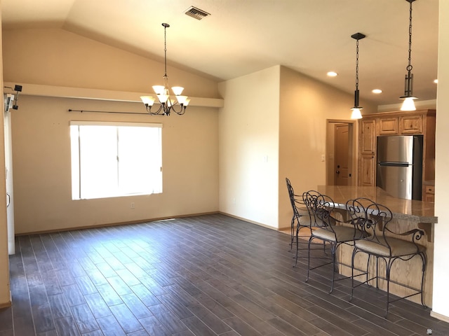 kitchen with dark wood-type flooring, a notable chandelier, stainless steel fridge, lofted ceiling, and a breakfast bar area