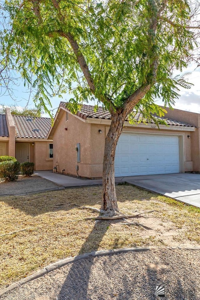 view of front of property featuring stucco siding, a garage, concrete driveway, and a tile roof