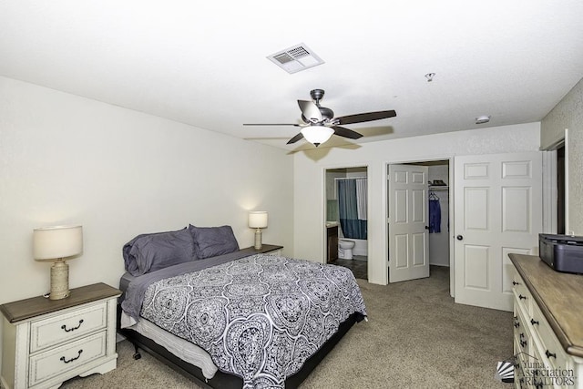 carpeted bedroom with visible vents, connected bathroom, a walk in closet, ceiling fan, and a closet