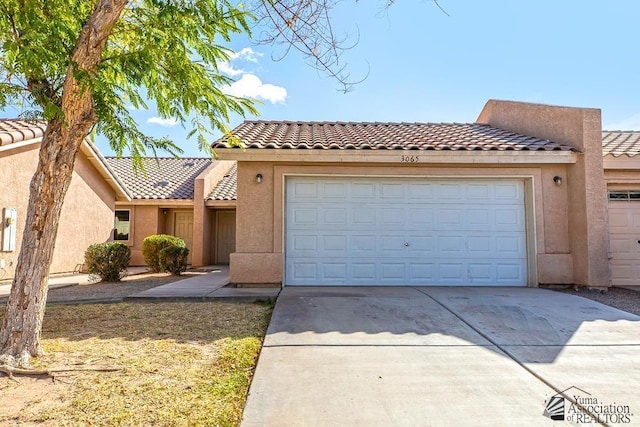 view of front of property with stucco siding, a garage, and a tiled roof