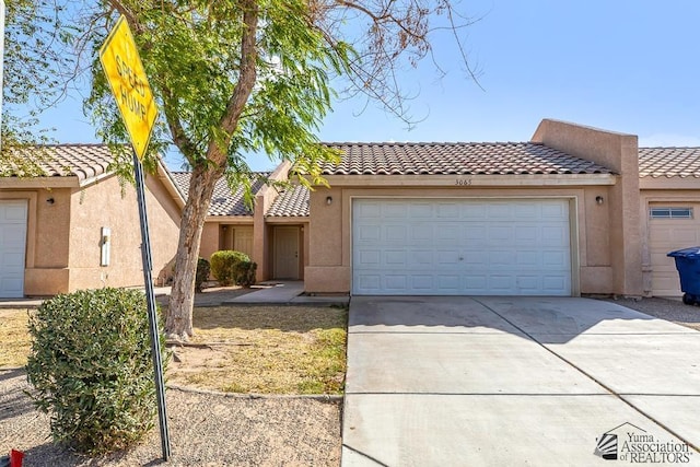 view of front of house featuring a tiled roof, stucco siding, an attached garage, and concrete driveway