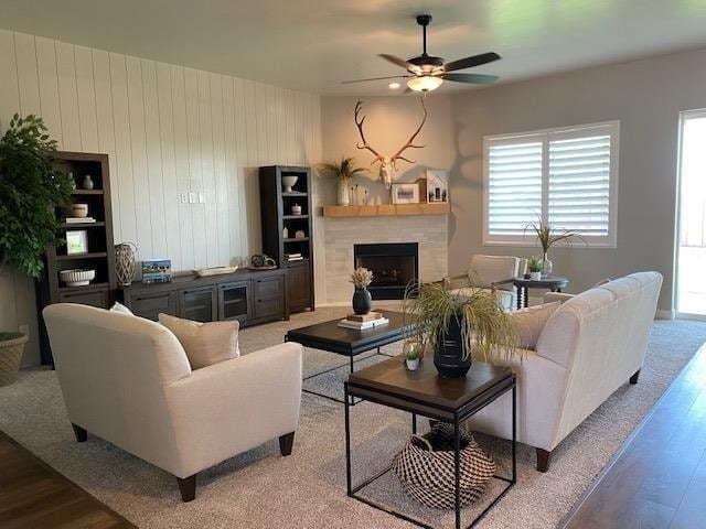 living room with hardwood / wood-style flooring, ceiling fan, and wooden walls