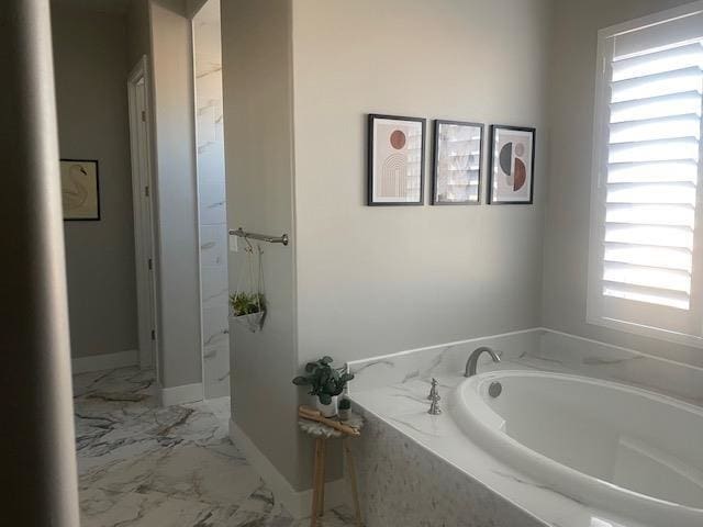 bathroom with a relaxing tiled tub and a healthy amount of sunlight