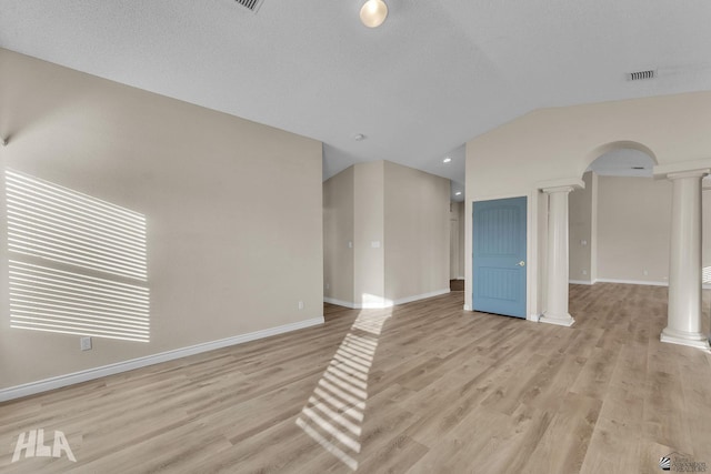 empty room with lofted ceiling, decorative columns, a textured ceiling, and light wood-type flooring