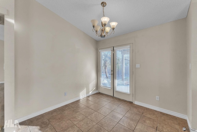 empty room with an inviting chandelier, light tile patterned floors, lofted ceiling, and a textured ceiling