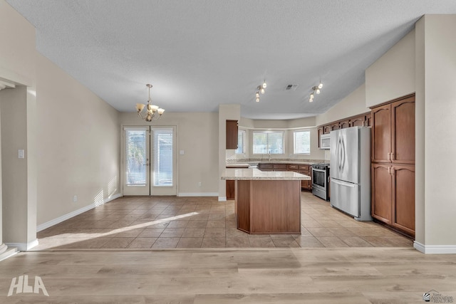 kitchen featuring light tile patterned flooring, a center island, vaulted ceiling, pendant lighting, and stainless steel appliances