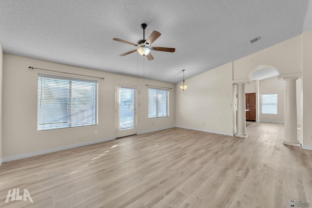 unfurnished living room featuring lofted ceiling, light hardwood / wood-style flooring, a textured ceiling, ceiling fan, and decorative columns