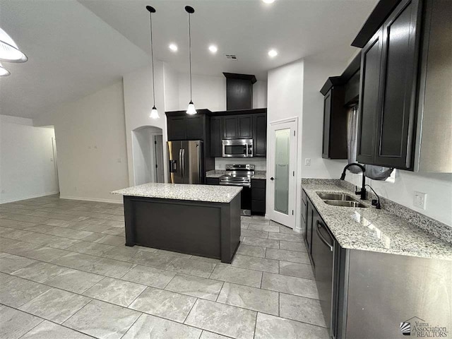 kitchen featuring stainless steel appliances, sink, decorative light fixtures, a high ceiling, and a kitchen island