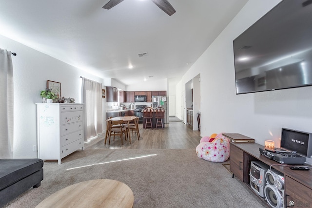 carpeted living room featuring ceiling fan and vaulted ceiling