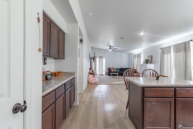 kitchen featuring dark brown cabinetry, light hardwood / wood-style floors, a kitchen island, and ceiling fan