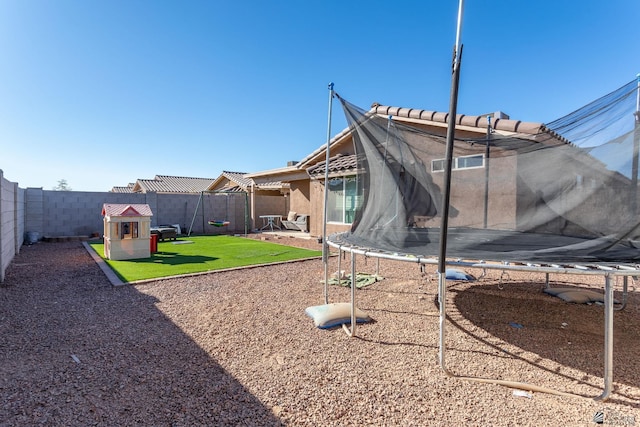 back of house featuring a trampoline and a lawn