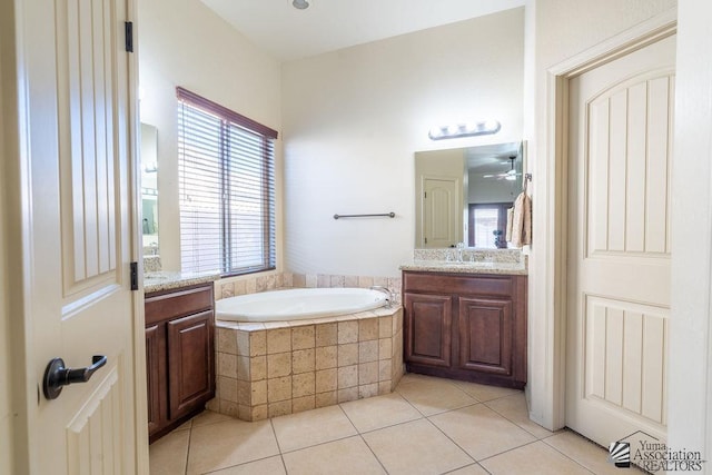 bathroom with tile patterned floors, vanity, a relaxing tiled tub, and ceiling fan