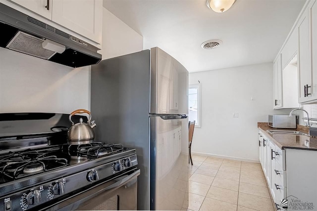 kitchen featuring dark stone counters, black range oven, sink, light tile patterned floors, and white cabinetry