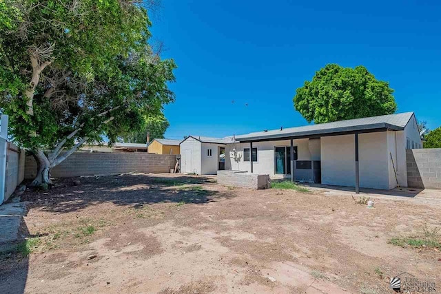 rear view of property with a storage shed