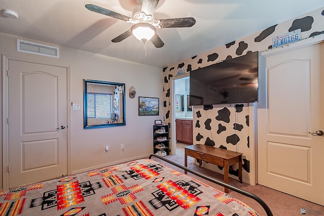 bedroom featuring ceiling fan, ensuite bathroom, light colored carpet, visible vents, and baseboards