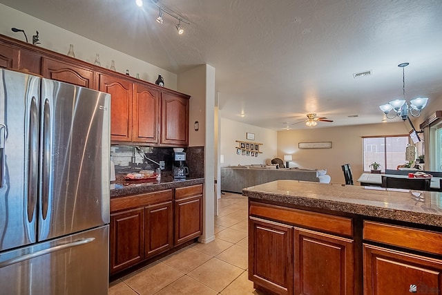 kitchen with light tile patterned floors, tile counters, visible vents, freestanding refrigerator, and ceiling fan with notable chandelier