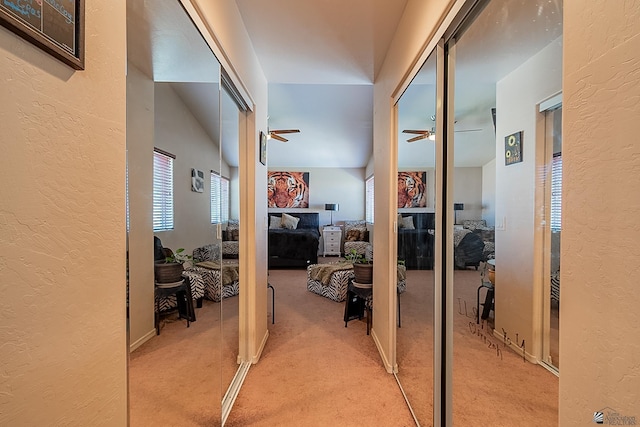 corridor featuring light carpet and a textured wall