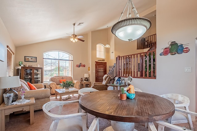 dining area featuring carpet, visible vents, stairway, a ceiling fan, and high vaulted ceiling