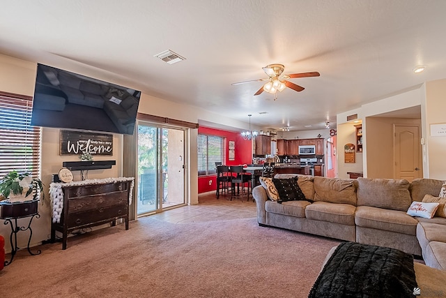 living room with light carpet, ceiling fan with notable chandelier, and visible vents