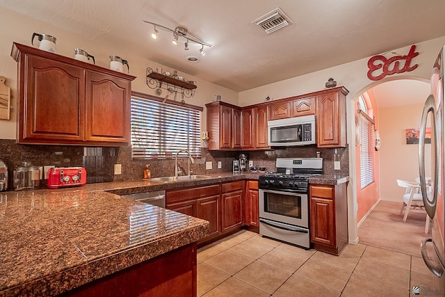 kitchen featuring visible vents, tile counters, decorative backsplash, appliances with stainless steel finishes, and a sink