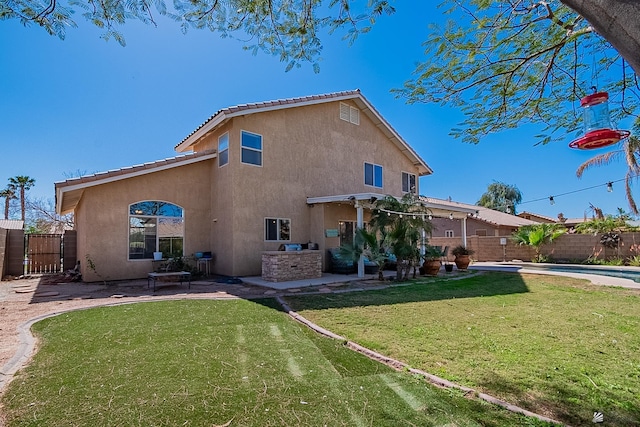 rear view of property with a fenced backyard, a lawn, a patio, and stucco siding