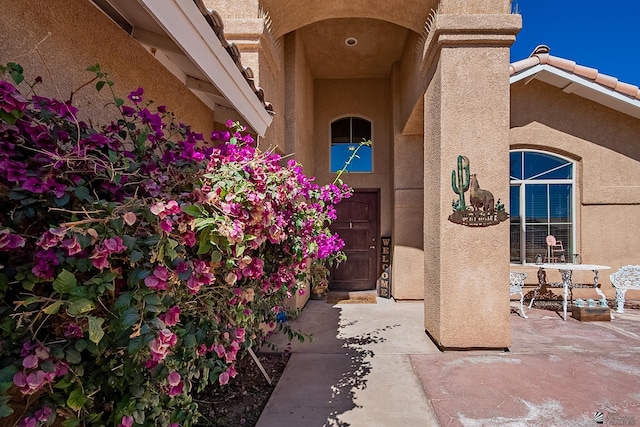 doorway to property featuring a tiled roof and stucco siding