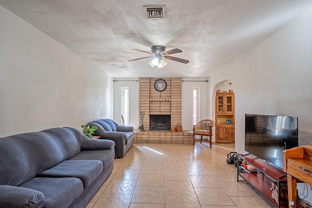 living area featuring a brick fireplace, light tile patterned flooring, visible vents, and a wealth of natural light