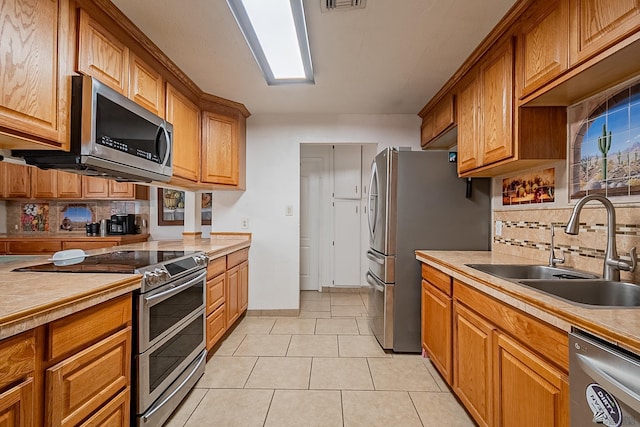 kitchen with brown cabinetry, stainless steel appliances, and a sink