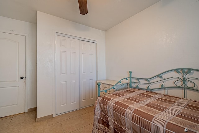 bedroom featuring light tile patterned floors, a ceiling fan, a closet, and baseboards