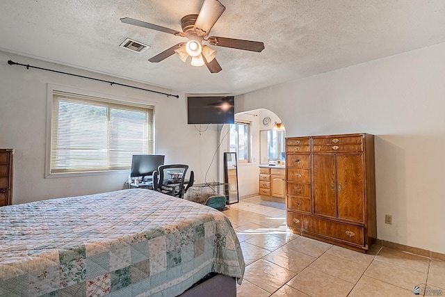 bedroom with visible vents, baseboards, arched walkways, a textured ceiling, and a ceiling fan