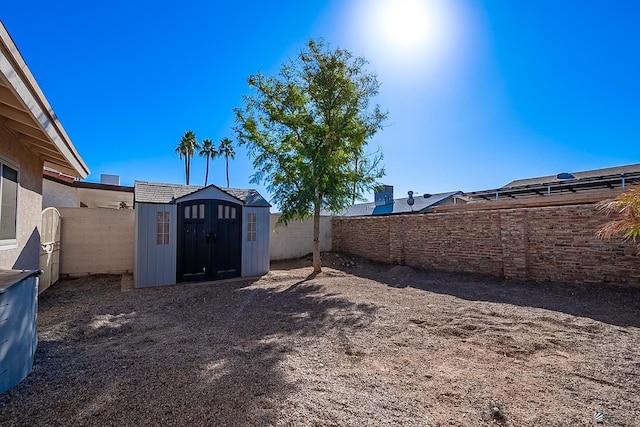 view of yard with a storage shed, a fenced backyard, and an outdoor structure