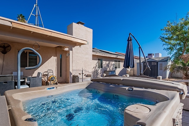 view of swimming pool with an outbuilding, fence, a shed, and a hot tub