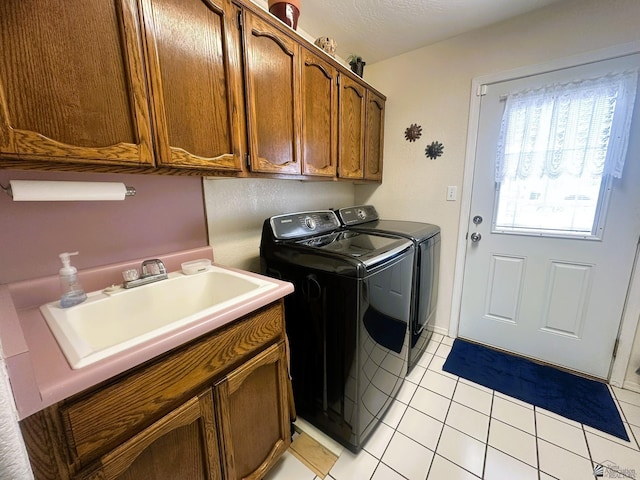 clothes washing area with light tile patterned floors, cabinet space, a sink, a textured ceiling, and independent washer and dryer