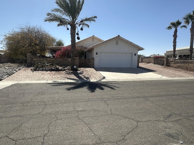 view of front of home featuring driveway, a garage, fence, and stucco siding