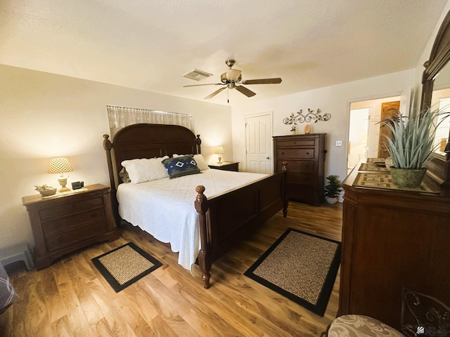 bedroom featuring a ceiling fan, visible vents, and wood finished floors