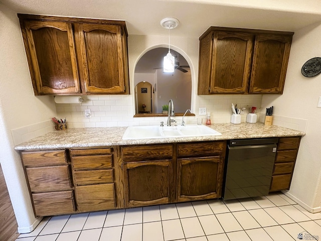 kitchen with black dishwasher, decorative backsplash, hanging light fixtures, light countertops, and a sink